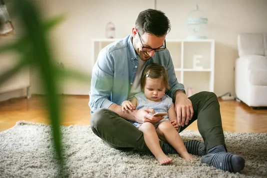 Vater und Tochter schauen auf Smartphone